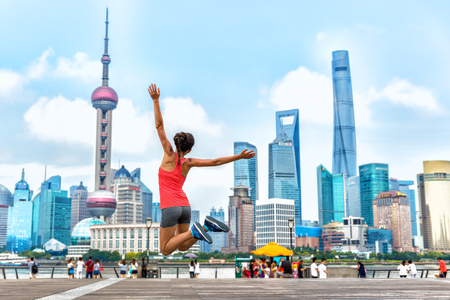 City success urban woman jumping of joy in Shanghai skyline background. Happiness, happy runner. Weight loss winning challenge concept.の写真素材