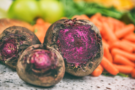 Beets and carrots farm vegetables fresh harvest background. Farmers market farming organic root vegetable closeup. Red beetroot beet and baby carrot with leafy greens and spinach, apples.の写真素材