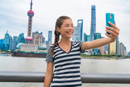 China travel Asian girl tourist taking phone selfie photo on the Bund in Shanghai city vacation....