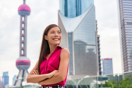 Chinese young woman portrait in Shanghai, China. Travel in Asia. Multiracial Asian Caucasian businesswoman smiling happy with Pearl tower and skyscrapers in the background. People lifestyle.の写真素材