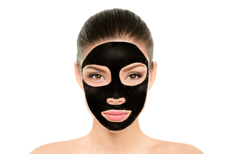Black charcoal mask facial treatment Asian beauty woman. Wellness and spa purifying peel off mask face portrait, isolated on white background. Cleansing skin care to remove blackheads and clean pores.の写真素材