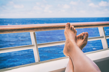 Cruise vacation travel woman relaxing with feet on balcony ship deck at view of ocean on honeymoon boat voyage destination. Relaxation lifestyle.の写真素材