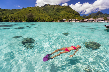 Luxury paradise travel vacation bikini woman relaxing snorkeling in idyllic ocean coral reefs at luxury overwater bungalows resort in Tahiti. French polynesia cruise lifestyle. Holiday girl getaway.の写真素材