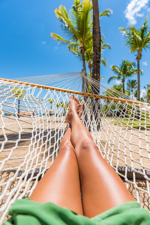 Beach hammock vacation woman feet selfie. Girl relaxing taking pov picture of her legs and feet sun tanning in tropical summer destination. Travel fun getaway.の写真素材