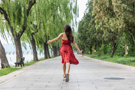 Carefree woman running of happiness and freedom in park in summer palace near Beijing city, china. Asia summer travel, tourist having fun. Joy and success concept.の写真素材