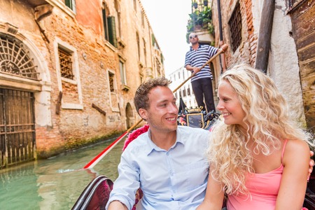 Honeymoon couple in Venice gondola romantic cruise happy tourists on summer luxury travel vacation. Young people in love smiling in boat ride in Venetian canals of old city, Italy. Europe holiday.の写真素材
