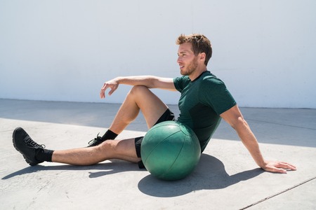 Fit athlete man relaxing at fitness gym during medicine ball workout. Healthy and active lifestyle young adult portrait.の写真素材