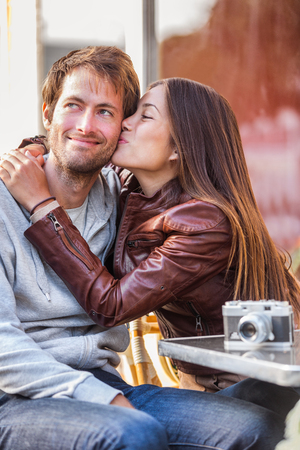 Girlfriend kiss couple young woman kissing boyfriend on holiday travel. Cafe lifestyle.の写真素材