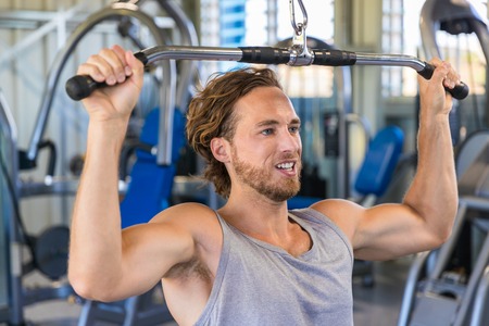 Shoulder pull down machine. Fitness man working out lat pulldown training at gym. Upper body...