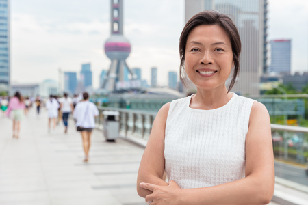 Happy Asian middle-aged businesswoman smiling portrait. Beautiful mature Chinese business woman in Shanghai, China.の写真素材