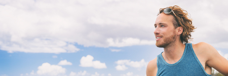 Young healthy smiling man portrait on sky background panorama banner.の写真素材