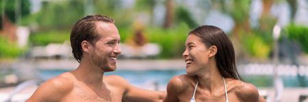 Happy couple having talking at luxury resort hotel travel beach holiday together on summer vacation. Asian woman, man relaxing by swimming poolの写真素材