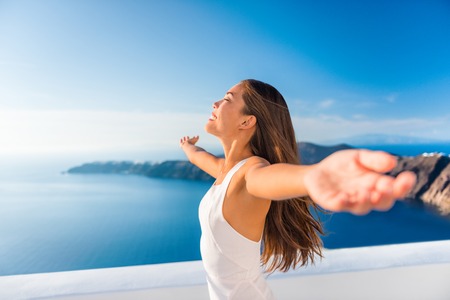 Europe cruise destination Santorini Greece travel vacation carefree woman enjoying freedom with open arms in famous travel holiday. Elegant Asian girl on greek travel luxury resort in Oia Santorini.の写真素材