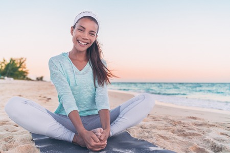 Yoga fitness beach woman stretching legs laughing. Happy Asian girl smiling during morning health workout. healthy active lifestyle.の写真素材
