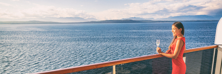 Luxury travel woman drinking wine on cruise ship at sunset. Asian girl relaxing enjoying Alaska scenery landscape. Panoramic banner.の写真素材