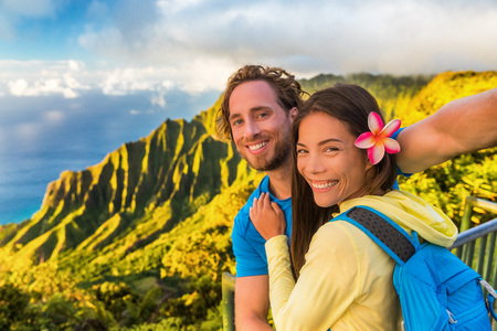 Na pali hikers couple tourists taking selfie at Napali lookout in Kauai Hawaii. Travel friends taking smartphone picture at famous destination Kalalau hawaiian attraction.の写真素材