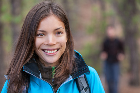 Healthy woman hiking outdoors. Happy young hiker girl walking in woods with group of friends. Smiling Chinese tourist.の写真素材