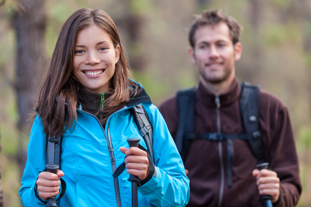 Happy young multiracial people hiking outdoors in nature forest. Smiling Asian woman and Caucasian man in autumn.の写真素材