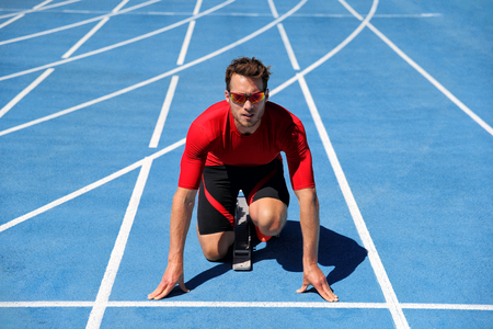 Runner athlete starting running at start of run track on blue running tracks at outdoor athletics...