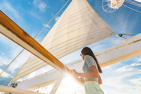 Luxury cruise ship vacation woman on yacht deck at sunset. Travel in Tahiti sail and mast on sky. Boat passenger sailing away on tropical getaway traveling in French Polynesia.の写真素材