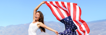 USA flag American woman waving the american flag in success. Asian girl cheering winner outdoors in...