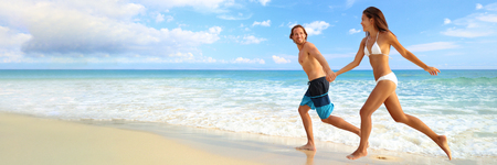 Beach vacation couple happy running of fun on landscape background banner. Young people tourists on tropical Caribbean holiday summer travel.の写真素材