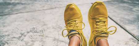 Sport running shoes woman taking feet selfie at gym -banner panorama. Sportswear yellow color fashion trainers with matching socks.の写真素材
