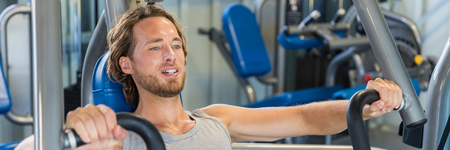 Portrait of fitness man working out chest muscles with vertical bench press machine. Difficult...