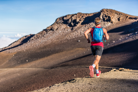 Trail runner man running with backpack on volcano mountain. Ultra marathon race athlete on volcanic path run in mountains landscape.の写真素材