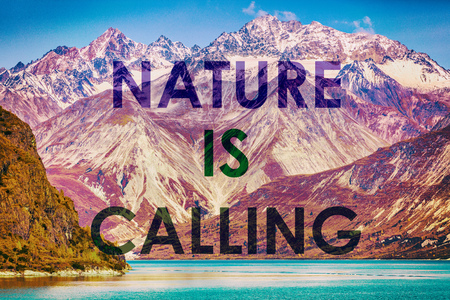 NATURE IS CALLING motivational quote on mountain range landscape sunset background. Outdoors inspiration to go travel in nature. Snow capped peaks of Alaska. USA.の写真素材