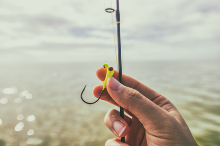 Fishing hook closeup watersport gear. Woman hand holding line.の写真素材