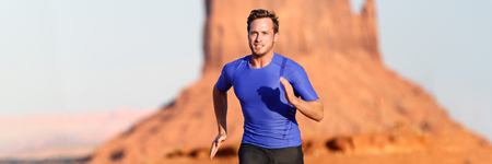 Running man sprinting cross country trail run. Male fit sport fitness model training for marathon outside in beautiful landscape. Caucasian handsome athlele in his 20s. Panoramic banner.の写真素材