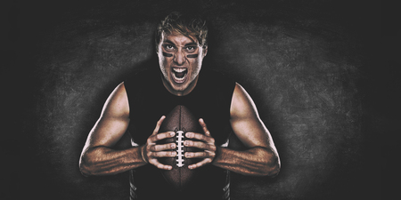 American football player screaming on black chalkboard texture background copy space for advertising. Panoramic banner blackboard with man athlete ready to play face paint black eye.の写真素材