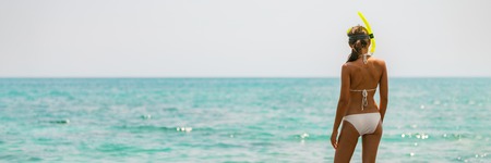 Beach vacation snorkel bikini woman going swimming in ocean with snorkeling mask on Caribbean holiday banner panorama. Summer vacation lifestyle.の写真素材