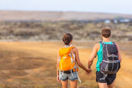 Hikers couple tourists walking together with backpacks holding hands walking in love. Young lovers travelers on travel adventure trek hike wanderlust. Nature trail travel people lifestyle.の写真素材