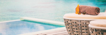 Luxury hotel swimming pool with sunbathing sunscreen lotion, sunglasses and towel background panoramic banner.の写真素材