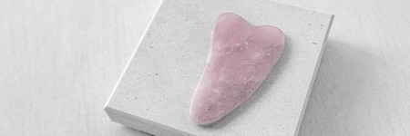 Pink rose quartz natural stone gua sha massaging tool for face massage banner panorama.の写真素材