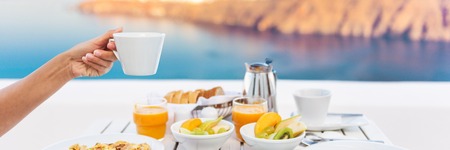 Cruise vacation breakfast woman drinking coffee at restaurant. Banner panorama of morning person eating holding coffee cup at luxury resort hotel.の写真素材