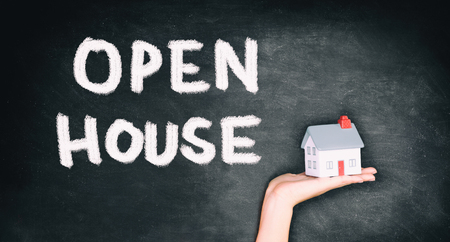 Open house real estate sale sign on black chalkboard texture with realtor hand showing home. House hunting.