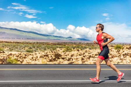 Triathlon runner triathlete man running in tri suit at ironman competition race on road. Sport athlete on marathon run training exercising cardio in professional outfit for triathlon. Fitness Hawaii.の写真素材