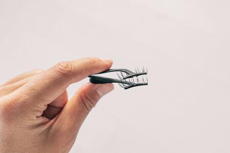 First person view of woman applying false magnetic eyelashes with metal applicator. Person holding pince to apply magnet fake lashes beauty trend.の写真素材
