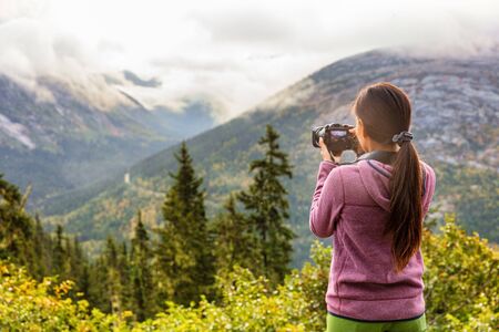 Outdoor travel lifestyle woman photographer shooting video camera at Alaska background. USA vacation...