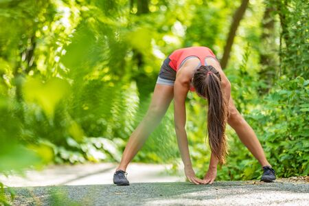 Runner athlete woman stretching doing leg stretch warm-up jogging for run outdoor summer spring.