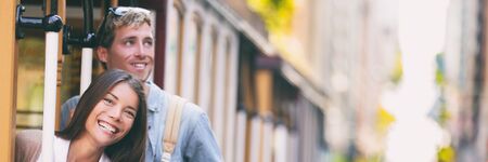 Tourists couple discovering San Francisco city by using public transport tram trolley streetcar transit system on streets. USA travel tourism panorama banner. Asian woman, Caucasian man.の写真素材