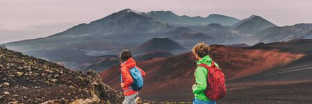 Hawaii Maui hikers couple hiking in mountains landscape banner panorama. Woman and man walking on hike of Haleakala volcano looking at view happy enjoying healthy outdoor lifestyle.の写真素材