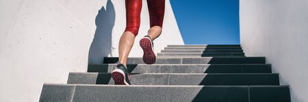 Cardio runner woman going up step of stairs at outdoor staircase for uphill hiit workout training exercise. Banner panoramic running shoes closeup.の写真素材