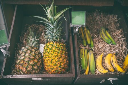 Pineapples and banana fruits for sale at farmer's market natural organic food. Fruit in wooden basket.の写真素材