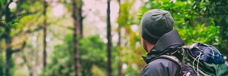 Hiking hiker man on hike with winter hat and bag in forest background landscape - Panoramic banner.