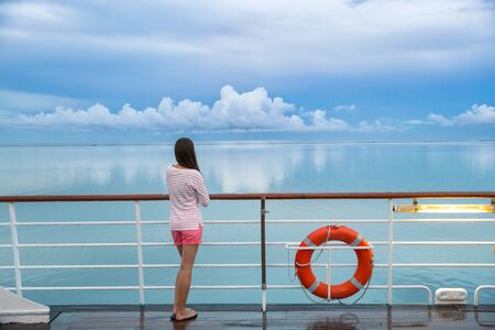 Cruise ship travel tourist woman on boat deck looking a peaceful summer night sky after rain. Serene...