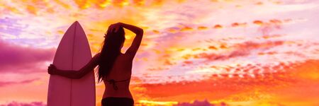 Hawaii surf summer vacation lifestyle. Silhouette of surfer woman at sunset with surfboard on beach. Banner panorama.の写真素材